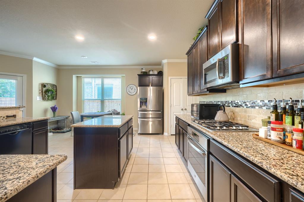 12417 Hitch Rack Way McKinney, TX 75071 - Photo 8 of 17 Kitchen featuring appliances with stainless steel finishes, a center island, tasteful backsplash, and light tile floors