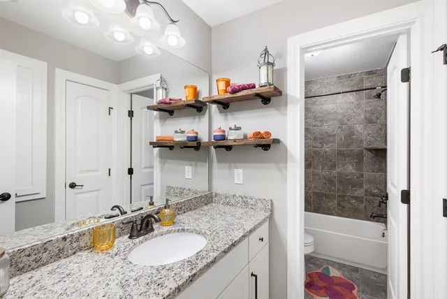 a bathroom with a granite countertop sink a mirror and shower