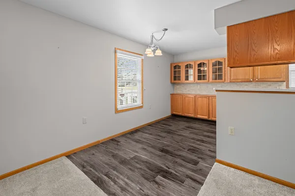an empty room with wooden floor cabinet and windows
