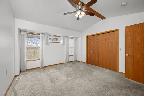 an empty room with windows and fan