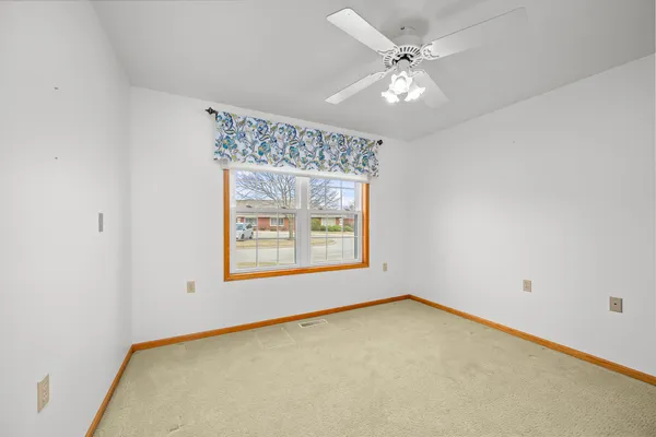 an empty room with a window and a ceiling fan
