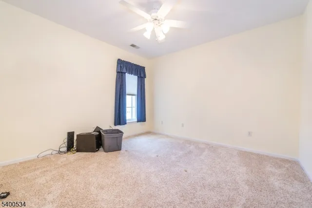 an empty room with a chandelier fan and windows