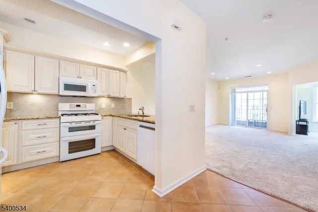 a kitchen with granite countertop white cabinets and white stainless steel appliances