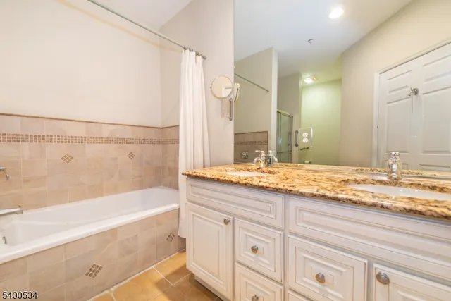a bathroom with a granite countertop sink mirror and a bath tub