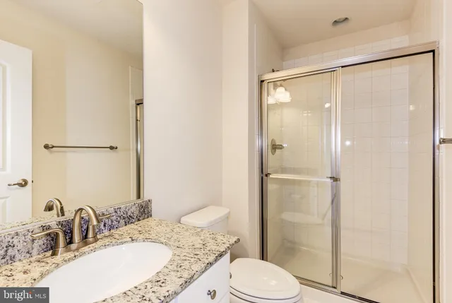 a bathroom with a granite countertop sink toilet and shower