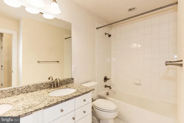 a bathroom with a granite countertop sink a toilet and shower