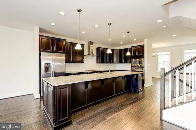 a large kitchen with a large counter top space a sink and stainless steel appliances