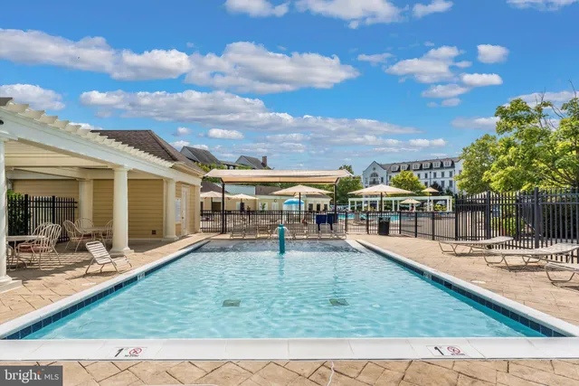 a view of a swimming pool with lawn chairs potted plants with sky view