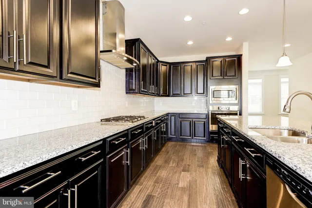 a kitchen with stainless steel appliances granite countertop lots of counter space a sink and a stove