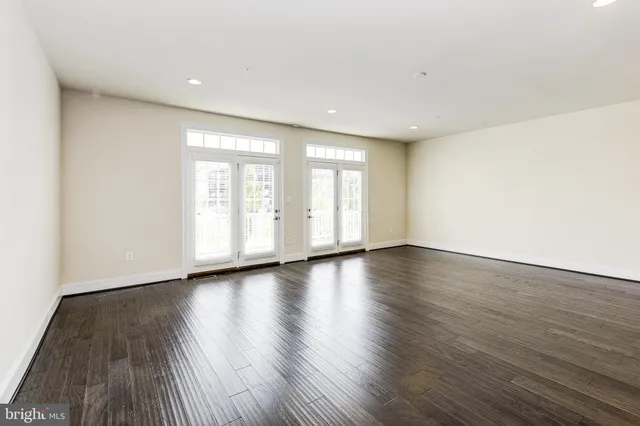 a view of an empty room with wooden floor and window