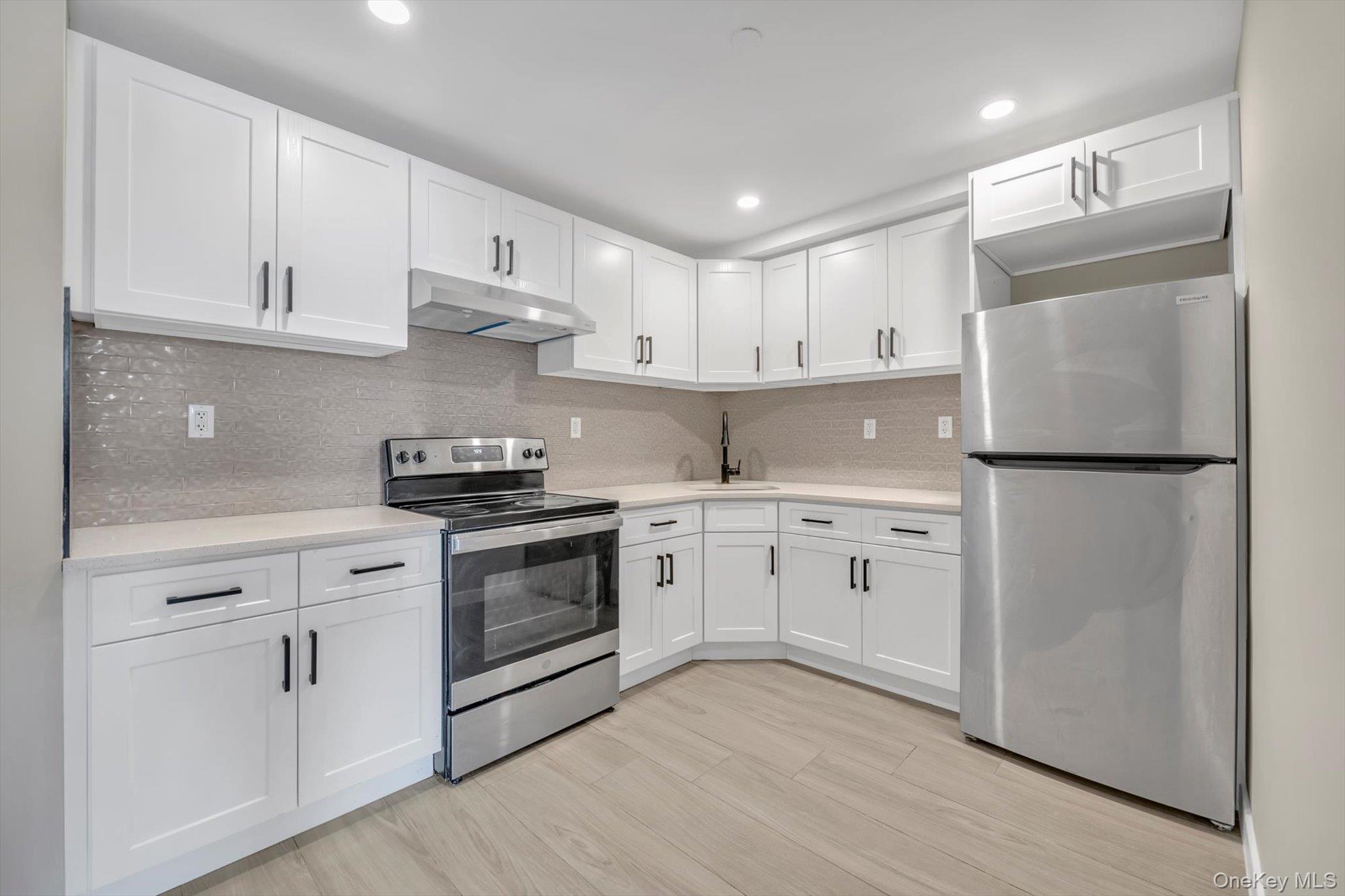 55-40 97th Place Queens, NY 11368 - Photo 5 of 11 a kitchen with white cabinets and white appliances