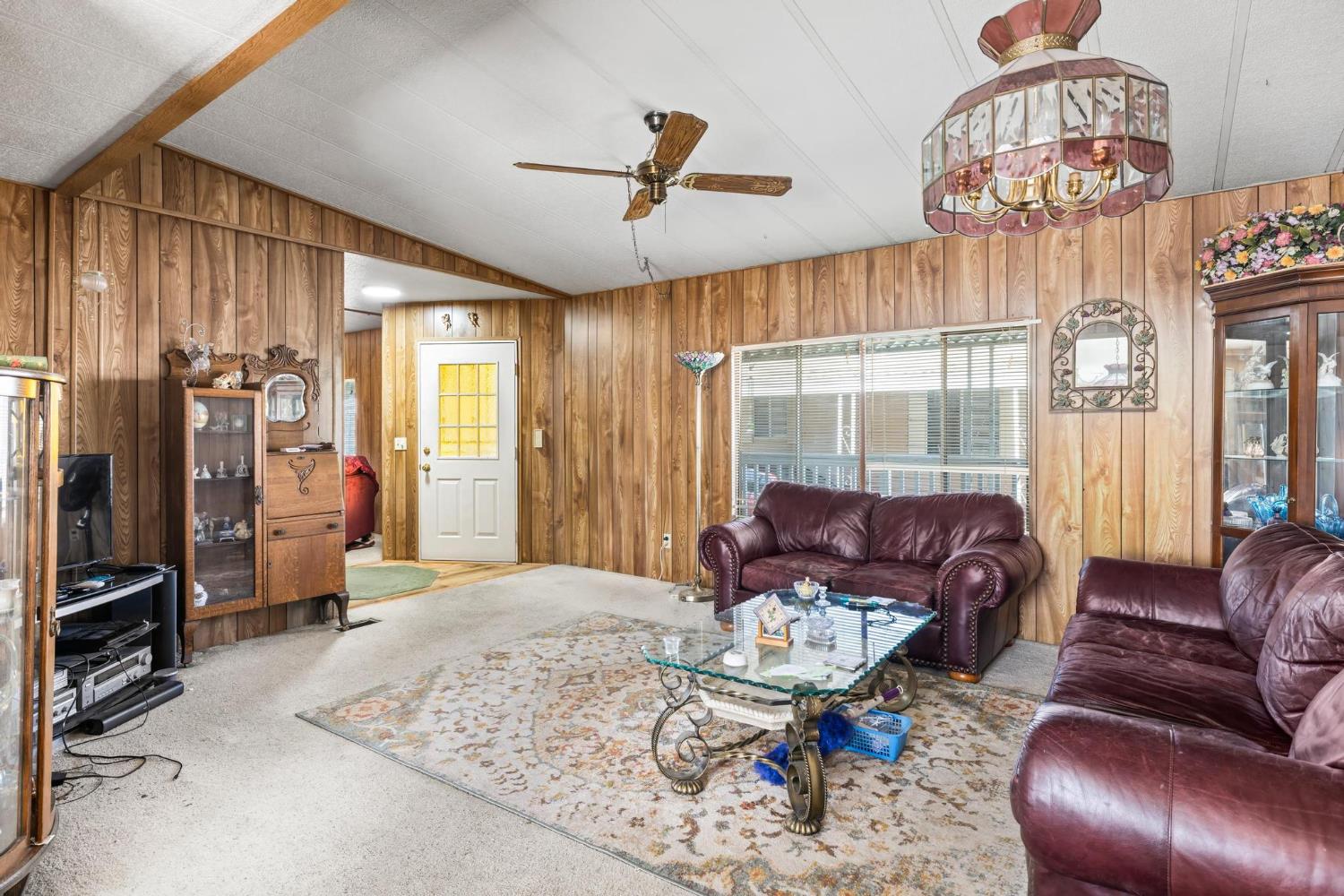 1200 South Carpenter Road, Unit 4 Modesto, CA 95351 - Photo 9 of 31 Living area featuring wood-panel walls, a vaulted ceiling with exposed beams, and carpet flooring