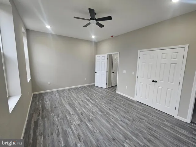 an empty room with wooden floor and a ceiling fan