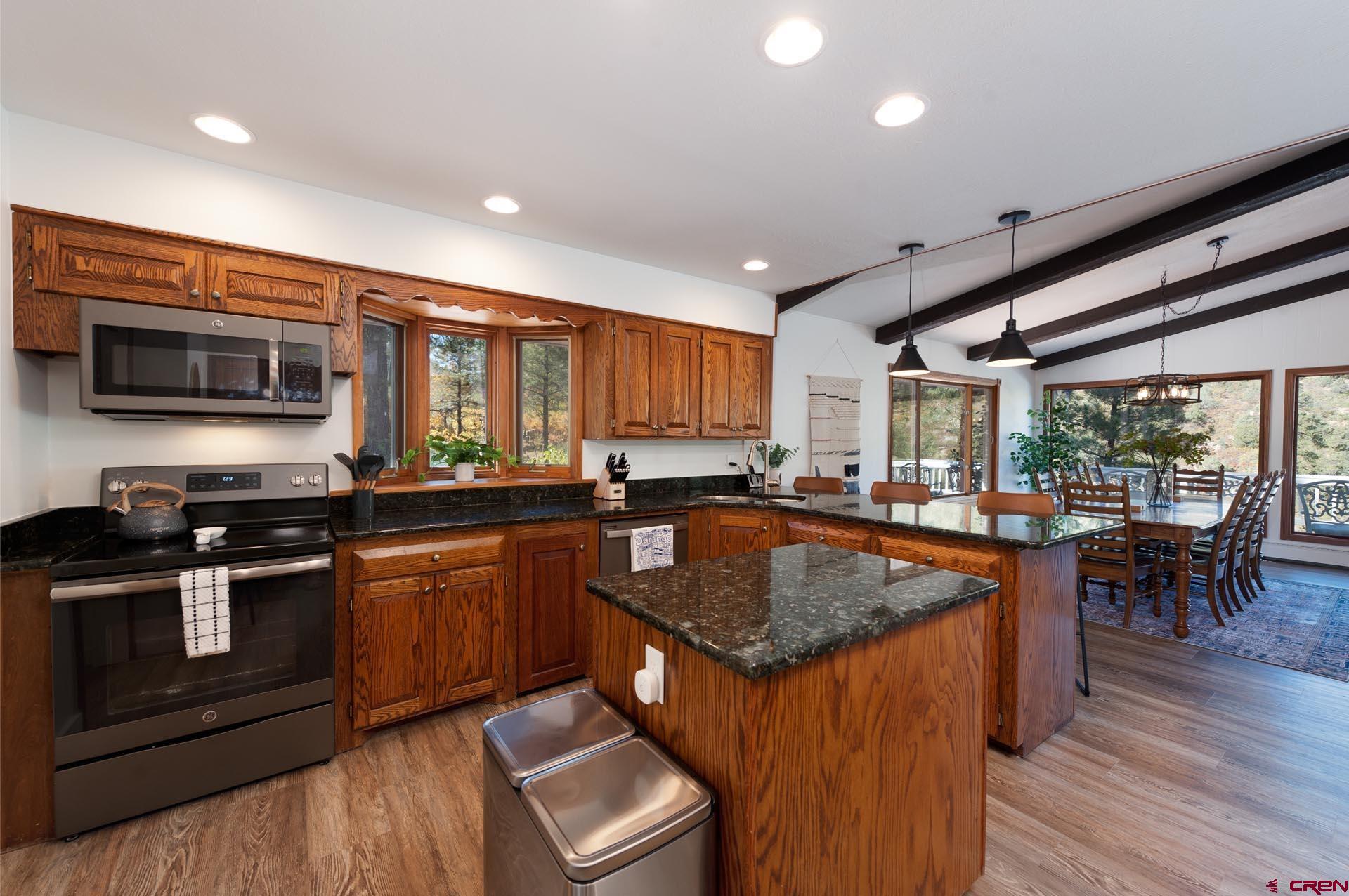 19 Newland Circle Durango, CO 81301 - Photo 13 of 44 a kitchen with stainless steel appliances granite countertop a stove a sink dishwasher a microwave oven and a dining table with wooden floor
