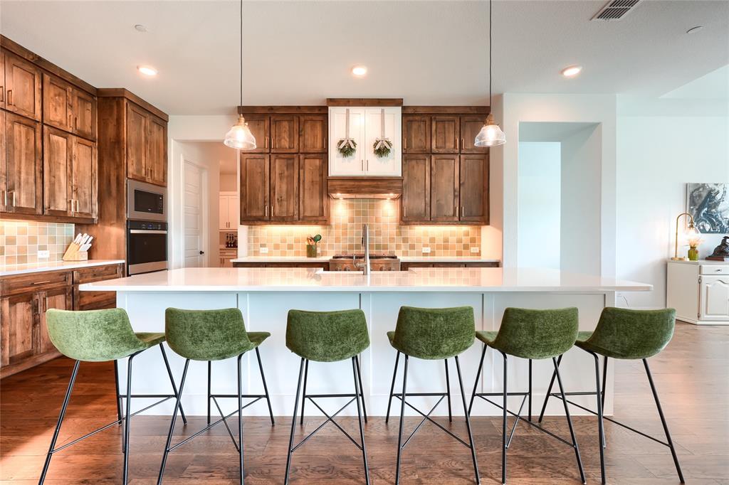 462 Infinito Drive Sunnyvale, TX 75182 - Photo 13 of 37 Kitchen featuring a breakfast bar area, a large island with sink, tasteful backsplash, hanging light fixtures, and stainless steel appliances