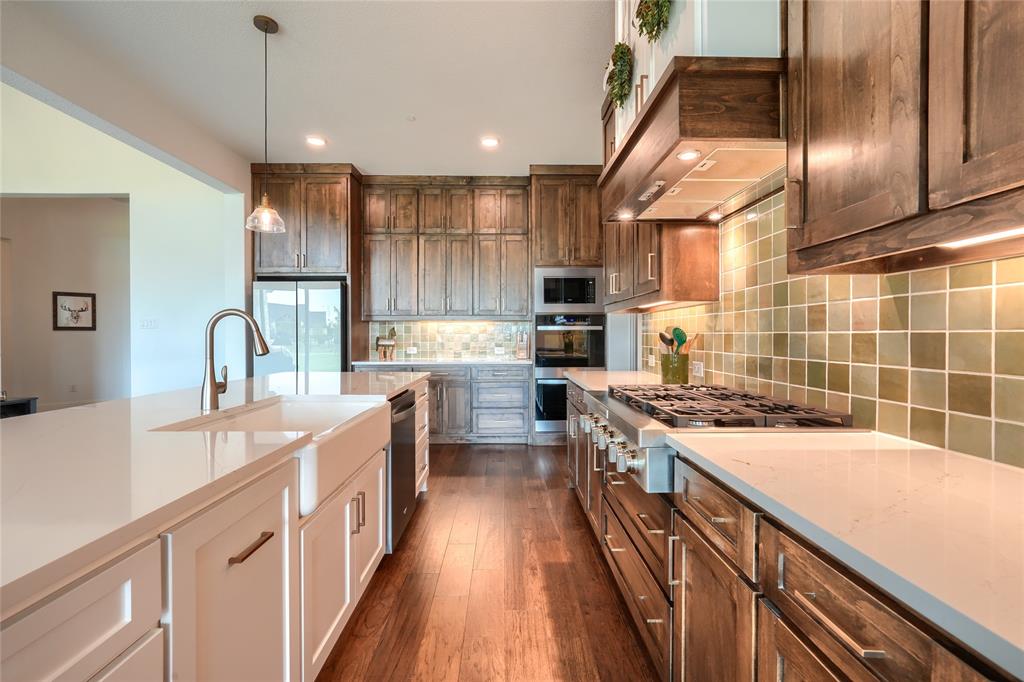 462 Infinito Drive Sunnyvale, TX 75182 - Photo 17 of 37 Kitchen with dual tone cabinets, stainless steel appliances, decorative light fixtures, decorative backsplash, and dark wood-style flooring