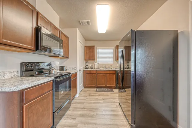 a large kitchen with stainless steel appliances granite countertop a refrigerator and a sink