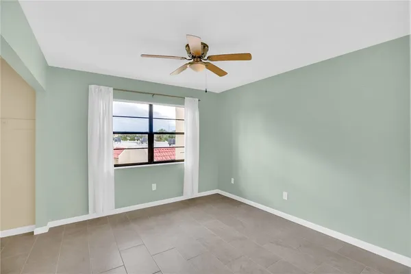 an empty room with windows and fan