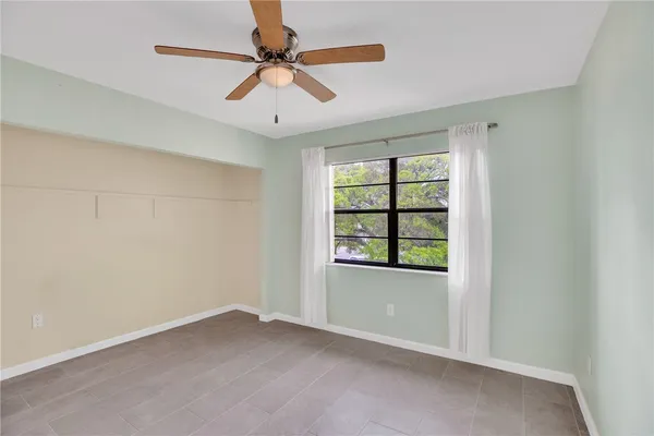 an empty room with a window and a ceiling fan