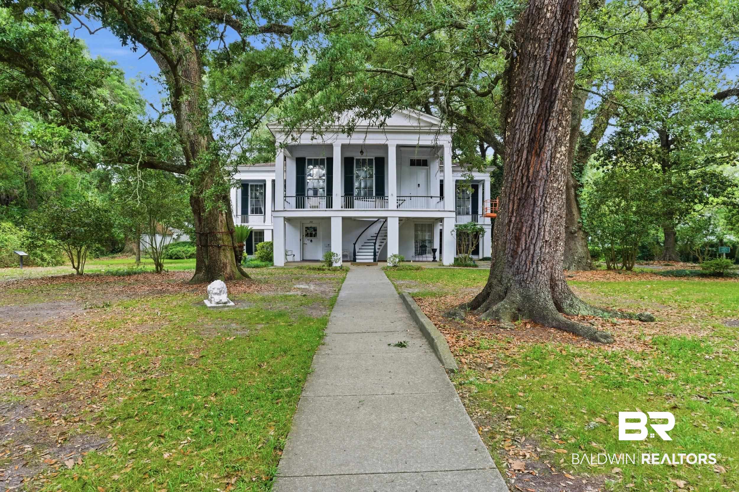350 Charles Street Mobile, AL 36604 - Photo 44 of 52 Grand white colonial-style home featuring a two-story columned front porch, a curved exterior staircase, and dark shutters