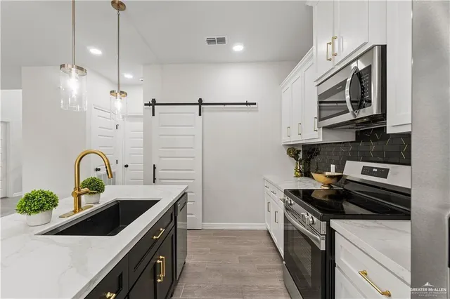 a kitchen with stainless steel appliances a sink a stove and cabinets