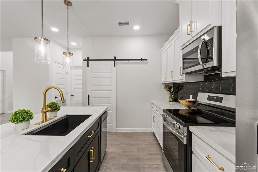5516 North Crown Point Pharr, TX 78577 - Photo 11 of 27 a kitchen with stainless steel appliances a sink a stove and cabinets