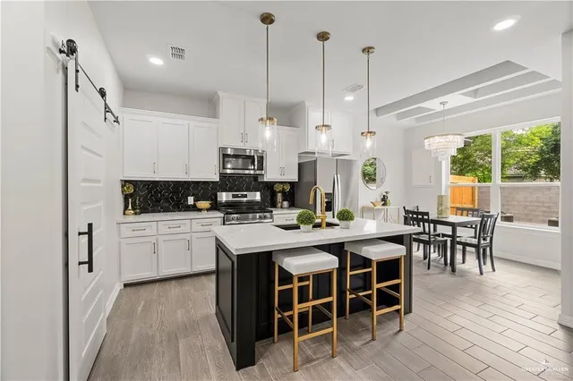 a kitchen with stainless steel appliances kitchen island granite countertop a table chairs sink and cabinets