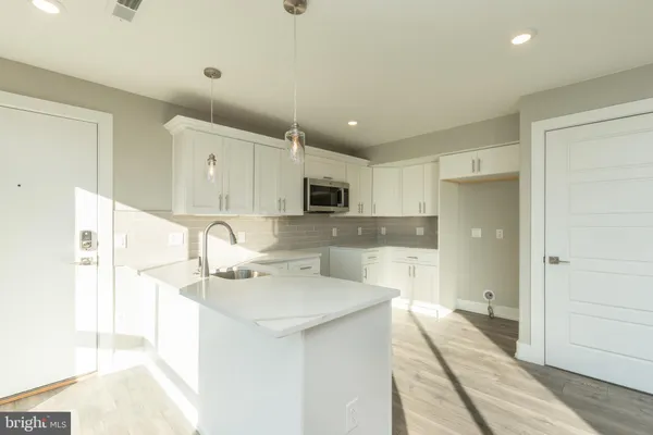a large white kitchen with a sink and dishwasher a refrigerator with wooden floor