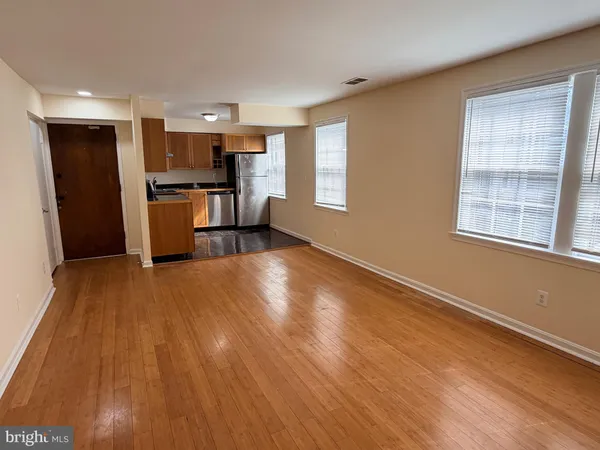 a view of an empty room with wooden floor and a window