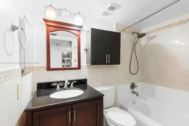 a bathroom with a sink vanity granite toilet tub and shower