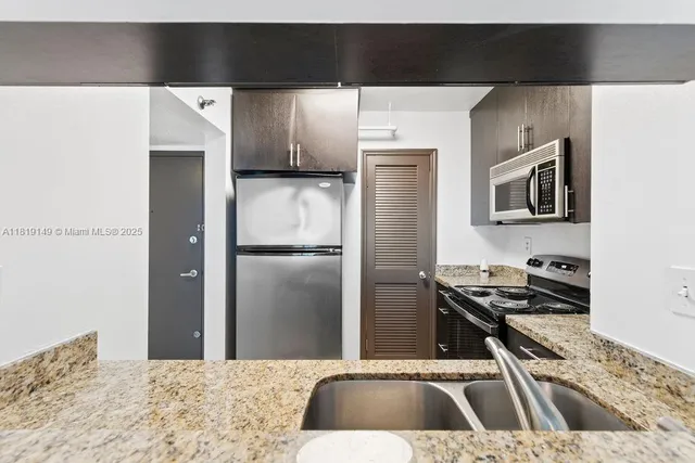 a kitchen with a sink a refrigerator and a stove top oven