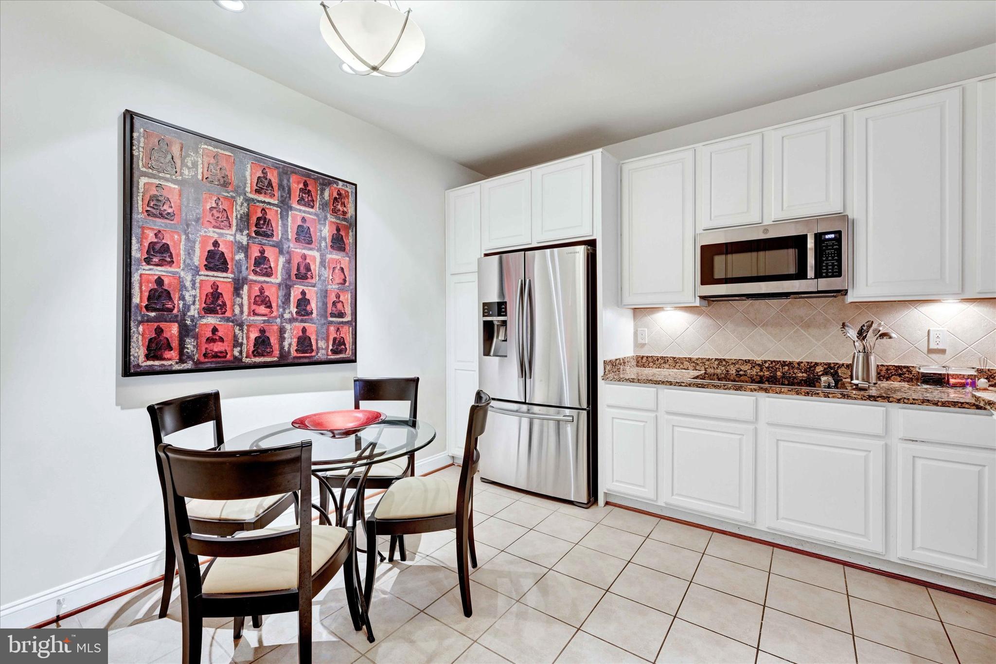 3000 Stone Cliff Drive, Unit 205 Baltimore, MD 21209 - Photo 12 of 28 a kitchen with stainless steel appliances kitchen island granite countertop a dining table chairs and a refrigerator