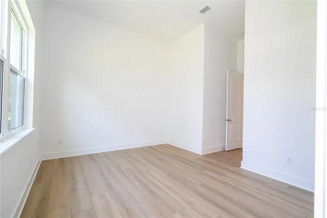 an empty room with wooden floor and windows