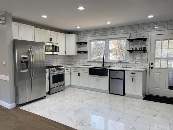 a kitchen with stainless steel appliances granite countertop a stove a sink dishwasher a refrigerator and a oven with wooden floor