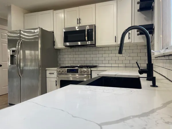 a kitchen with stainless steel appliances a refrigerator a sink a stove and microwave