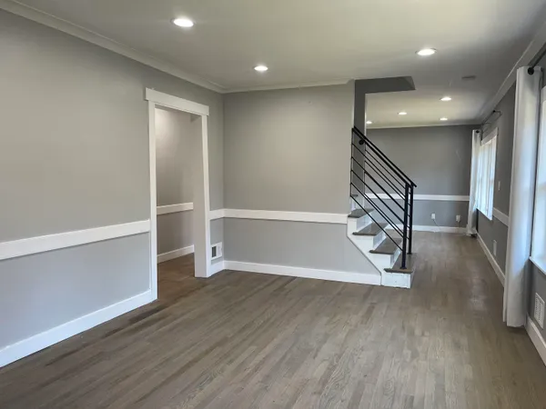 a view of an empty room with wooden floor and stairs