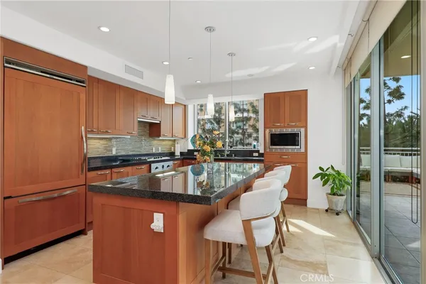 a kitchen with stainless steel appliances granite countertop a stove top oven a sink and a refrigerator