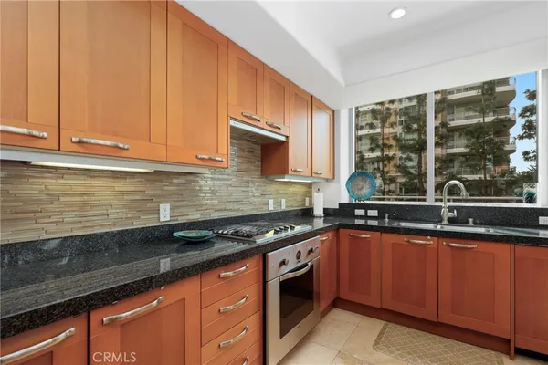 a kitchen with stainless steel appliances granite countertop sink stove refrigerator and cabinets