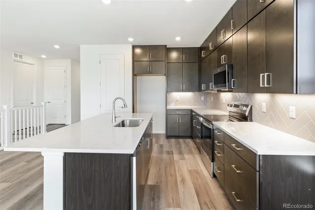 a kitchen with a sink a counter top space stainless steel appliances and cabinets