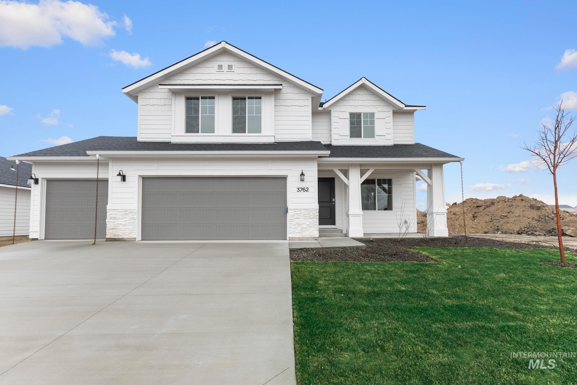 View of front of house with a porch, a front yard, driveway, and a shingled roof