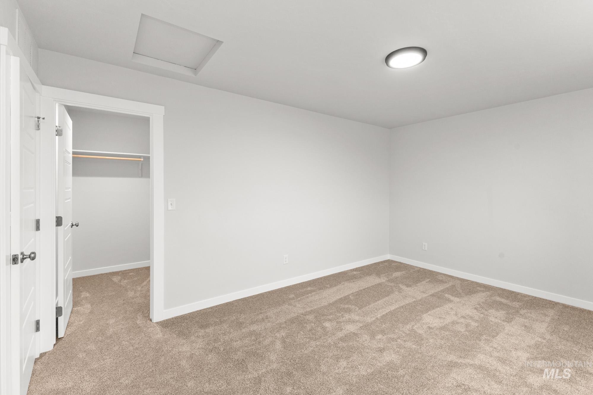 3762 West Maypearl Street Meridian, ID 83642 - Photo 16 of 29 Unfurnished bedroom featuring attic access, a walk in closet, and light colored carpet