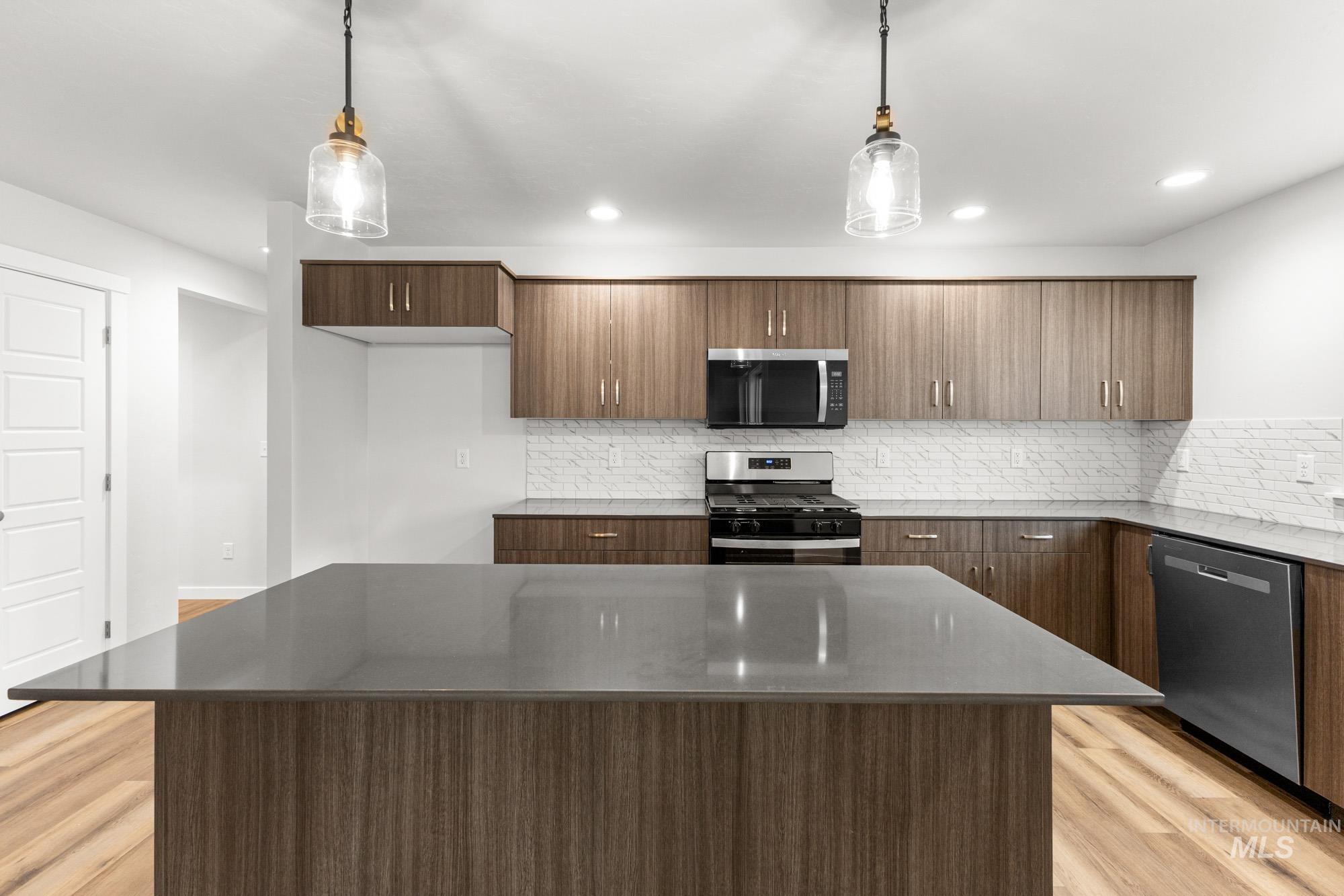 3762 West Maypearl Street Meridian, ID 83642 - Photo 3 of 29 Kitchen featuring appliances with stainless steel finishes, backsplash, hanging light fixtures, light wood-style floors, and a kitchen island