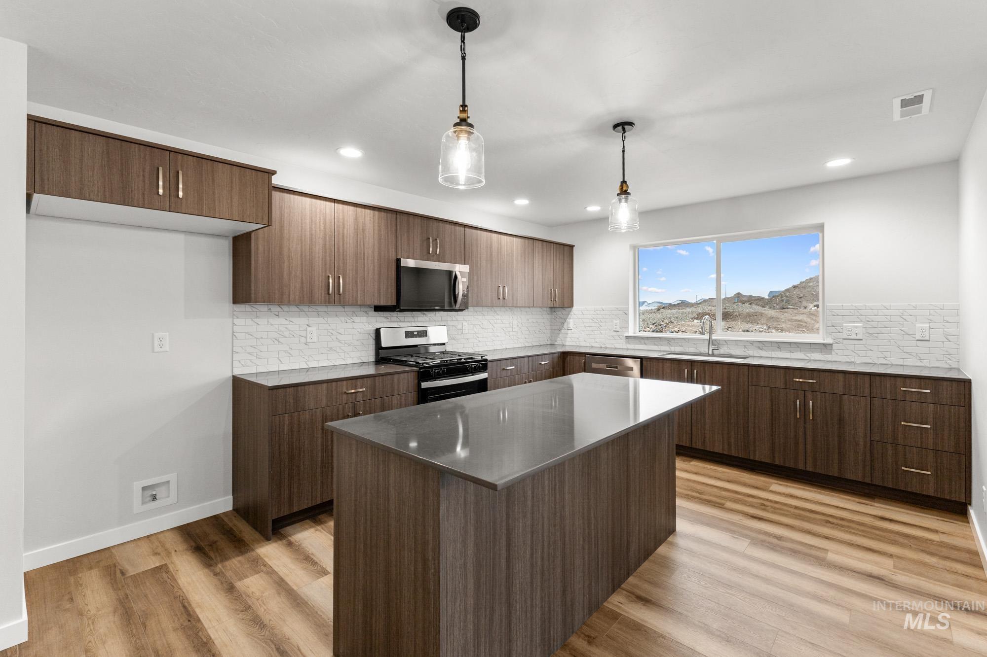 3762 West Maypearl Street Meridian, ID 83642 - Photo 4 of 29 Kitchen with appliances with stainless steel finishes, pendant lighting, decorative backsplash, light wood-style flooring, and recessed lighting