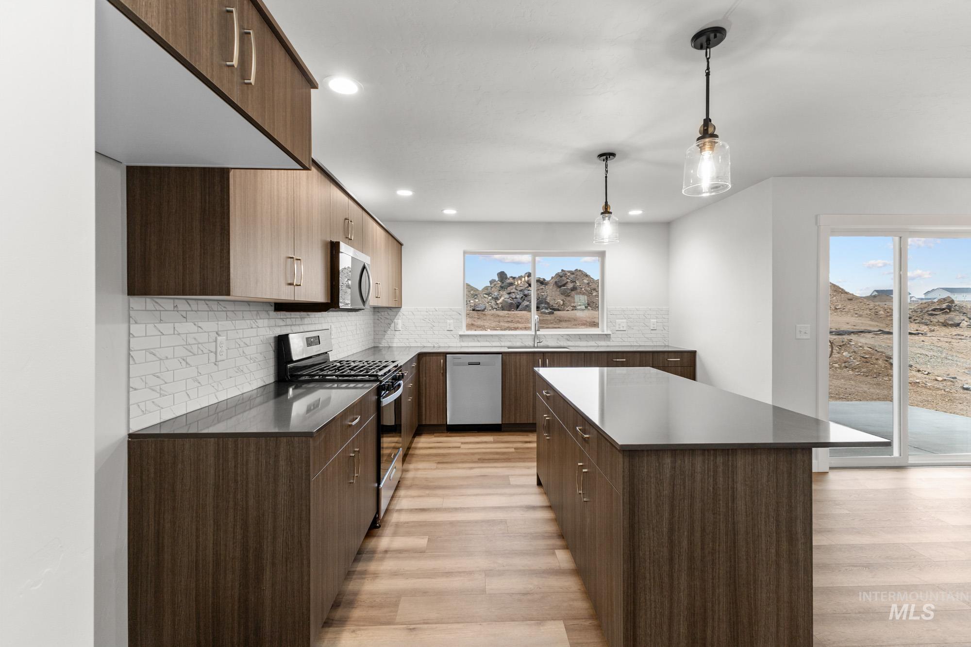 3762 West Maypearl Street Meridian, ID 83642 - Photo 5 of 29 Kitchen featuring appliances with stainless steel finishes, modern cabinets, a kitchen island, decorative light fixtures, and decorative backsplash