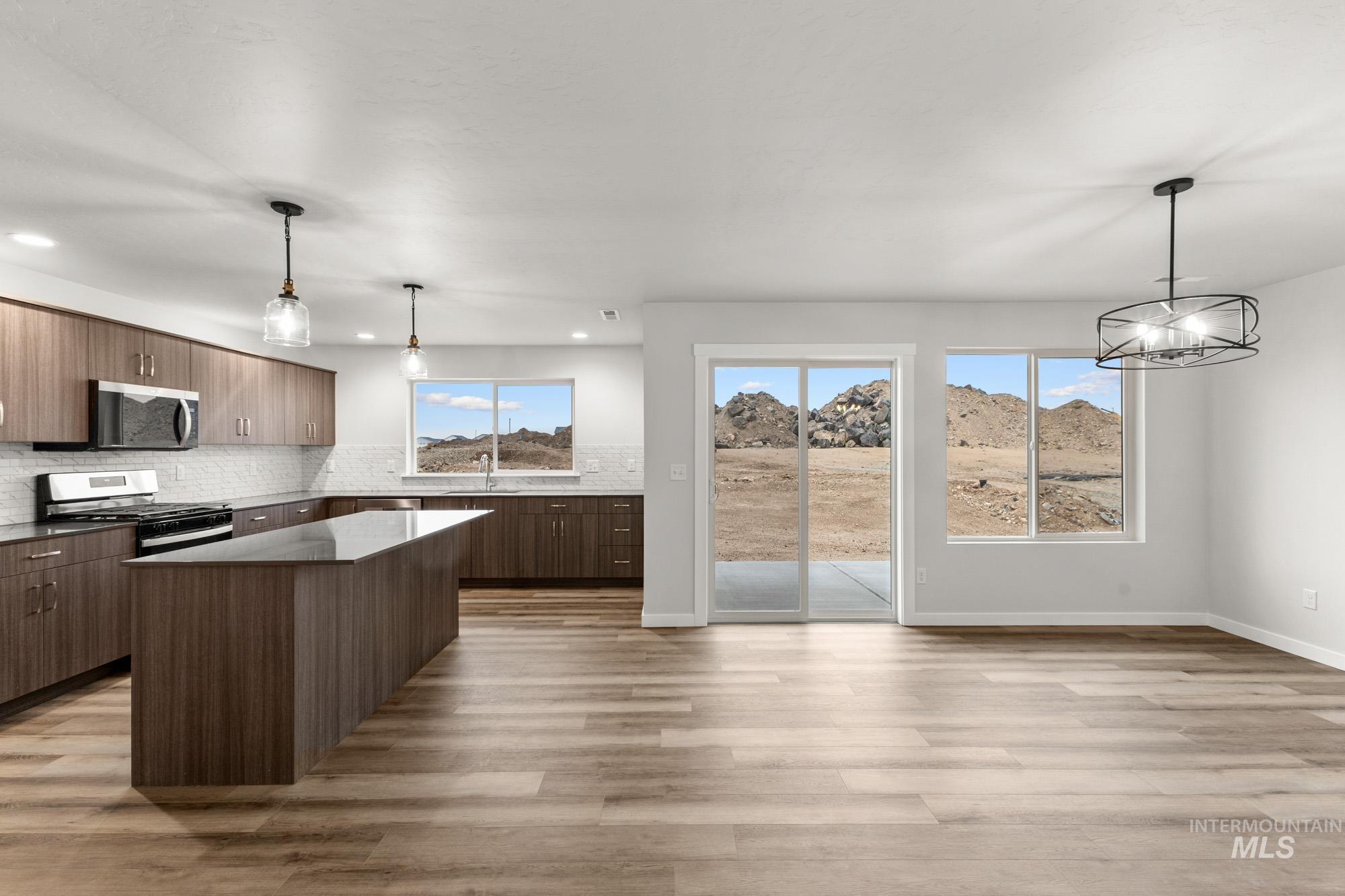 3762 West Maypearl Street Meridian, ID 83642 - Photo 6 of 29 Kitchen featuring decorative light fixtures, modern cabinets, a kitchen island, stainless steel appliances, and light wood-style floors