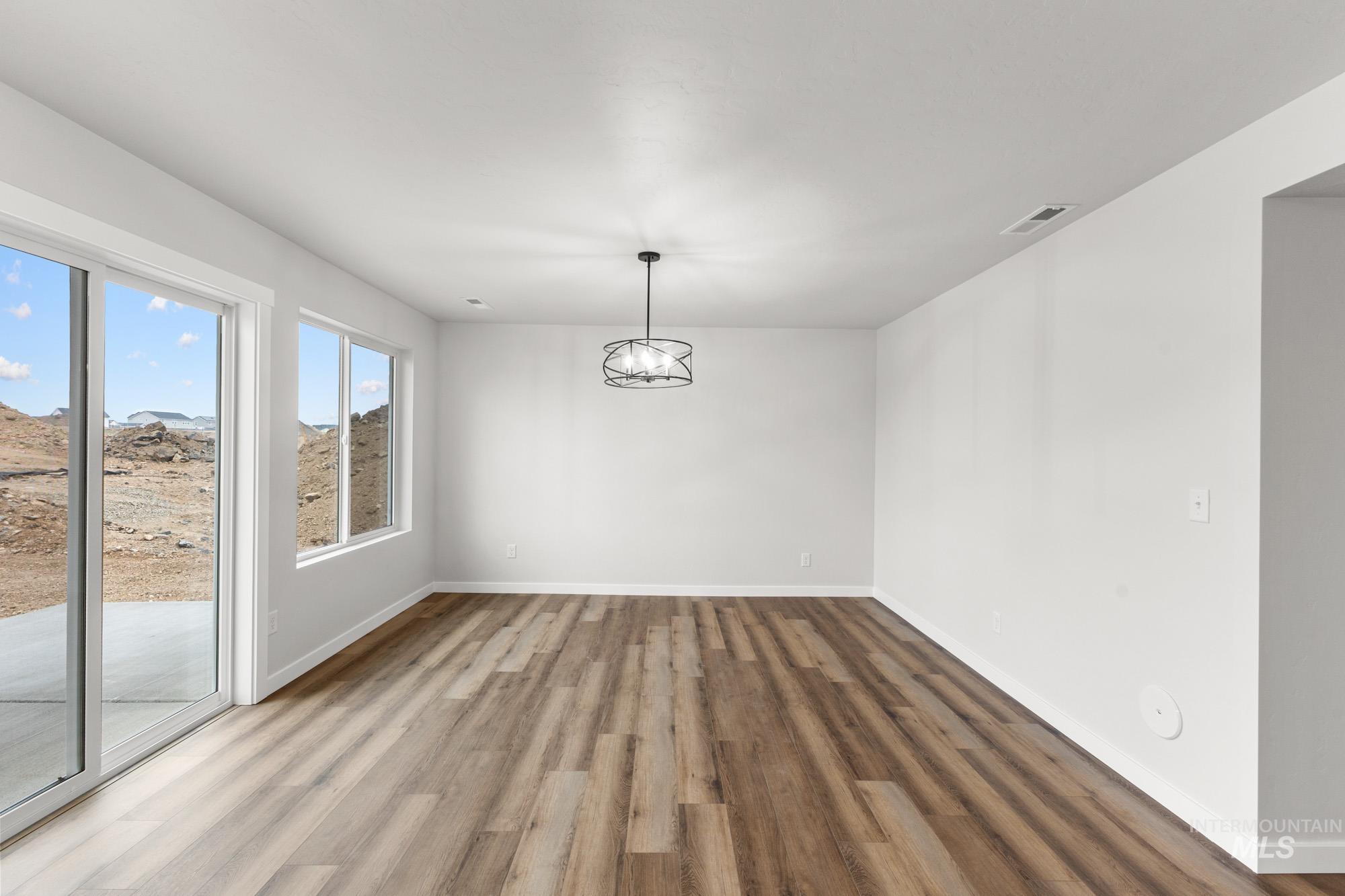 3762 West Maypearl Street Meridian, ID 83642 - Photo 7 of 29 Unfurnished dining area with wood finished floors and a chandelier
