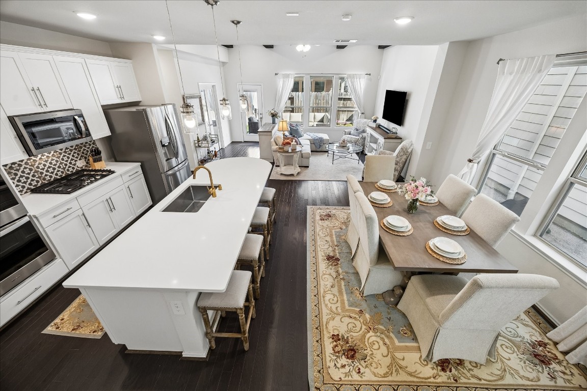 4026 Delta Rose Street Houston, TX 77018 - Photo 7 of 44 Open concept living featuring oversized island and bar seating, stainless appliances and custom cabinetry that flows into the dining and living areas with charcoal oak floors throughout, beam accents and views of the backyard.