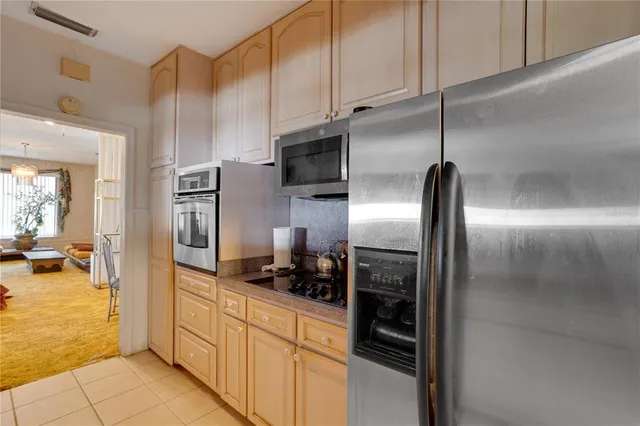 a kitchen with stainless steel appliances kitchen island granite countertop a refrigerator a stove and a sink with wooden floor