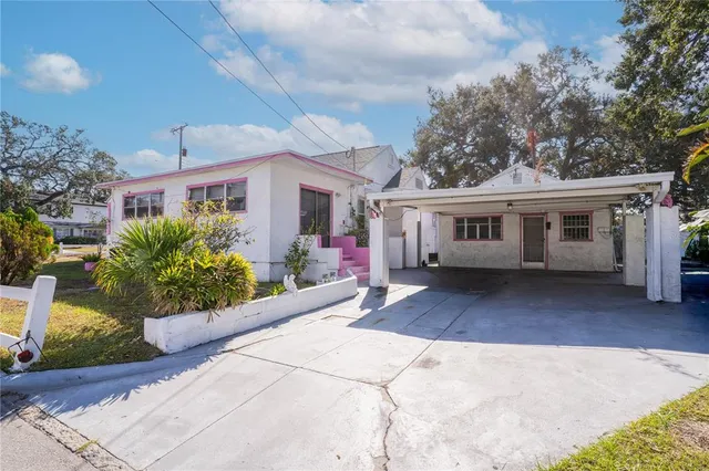 a view of a white house with a yard and potted plants