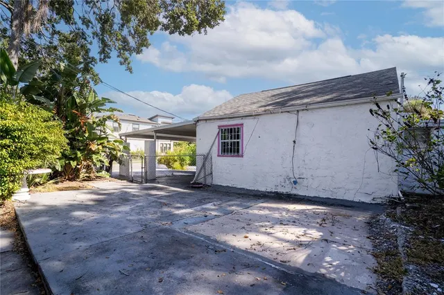 a view of a house with a small yard and a large tree